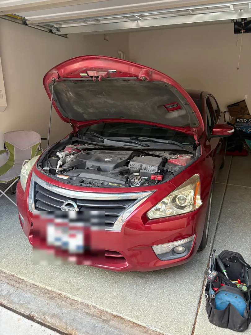 Red Nissan Altima with the hood open inside a residential garage during a mobile diagnostic - Perris, CA