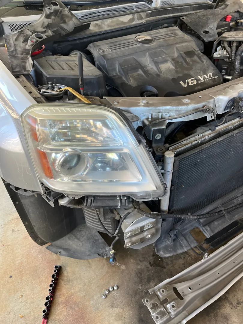 Front end of a V6 sedan disassembled with the headlight removed for radiator access - Perris, CA