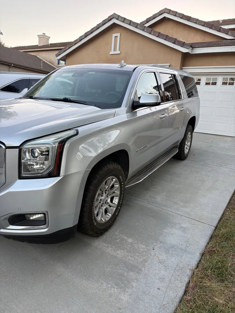 Front three-quarter view of a silver GMC Yukon XL in a suburban driveway - Menifee, CA
