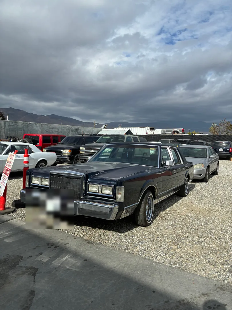 Front view of a 1988 Lincoln Town Car parked at a shop under a cloudy sky - Perris, CA