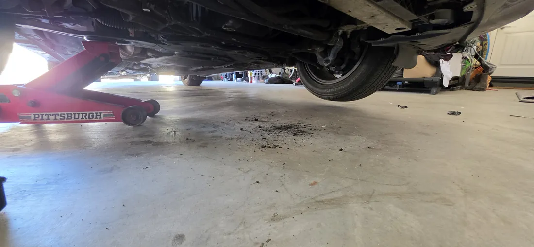 Floor-level view underneath a car raised on a jack during a serpentine belt diagnosis - Menifee, CA