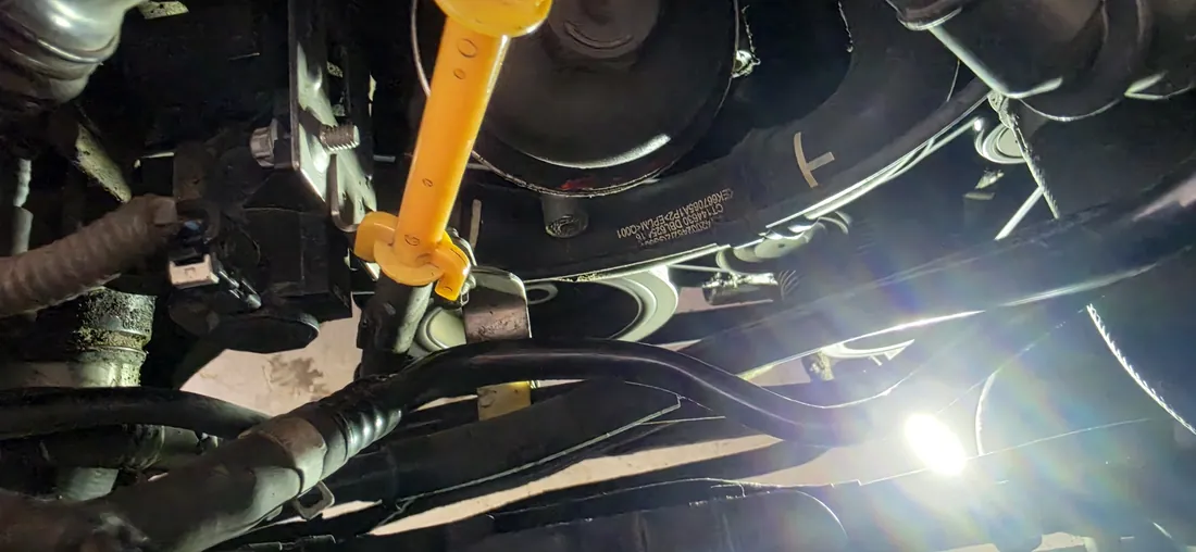 Mechanic working underneath a raised vehicle with a work light during a belt diagnosis - Menifee, CA