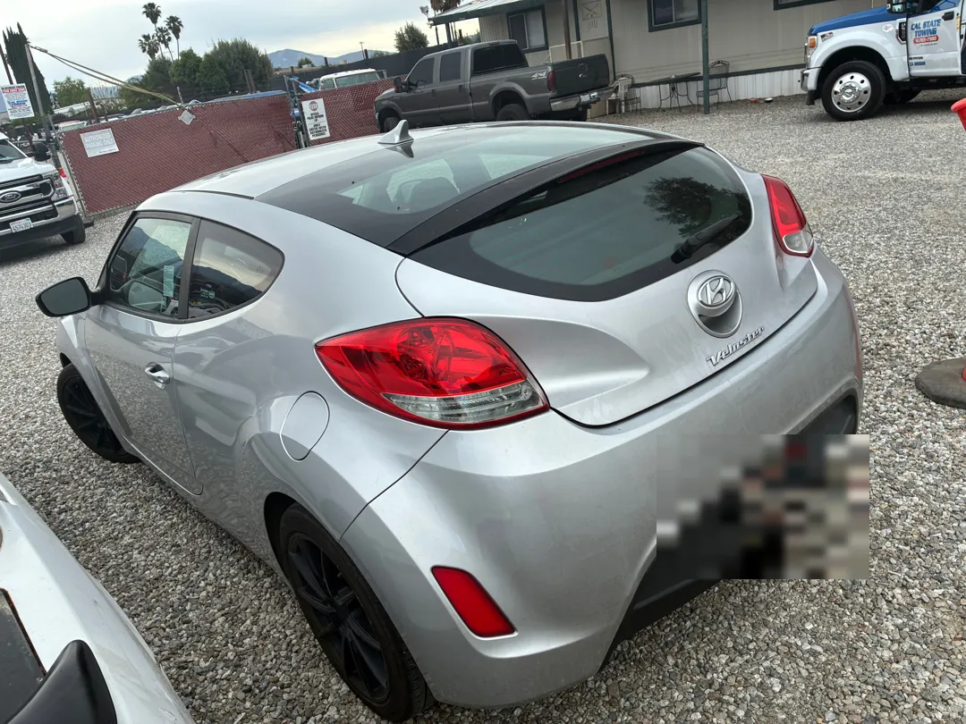 Rear three-quarter view of a silver Hyundai Veloster at the shop - Menifee, CA