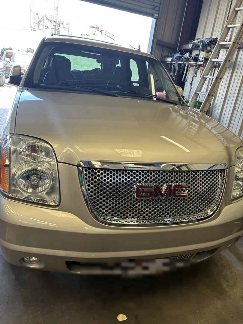 Front view of a gold GMC Yukon Denali inside a repair shop - Menifee, CA